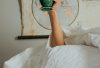 a person laying in bed with a cup in their hand