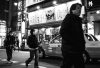 People cross a busy street at night in japan.