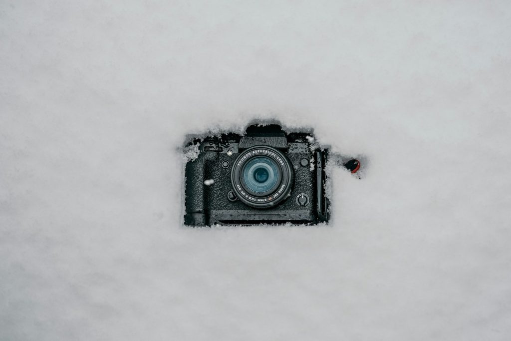 a camera sitting in the snow with a blue lens